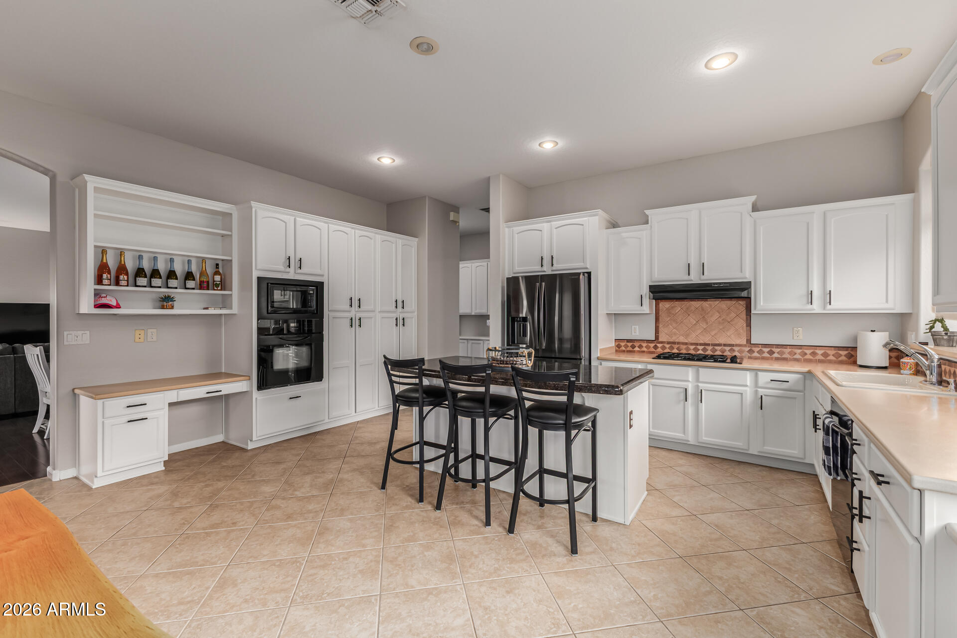 13318 West Coronado Road Goodyear, AZ 85395 - Photo 18 of 48 a kitchen with a refrigerator a stove top oven a sink dishwasher and a dining table with wooden cabinet
