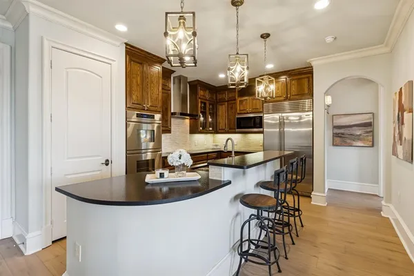 a kitchen with stainless steel appliances kitchen island granite countertop a refrigerator a oven a sink a dining table and chairs with wooden floor