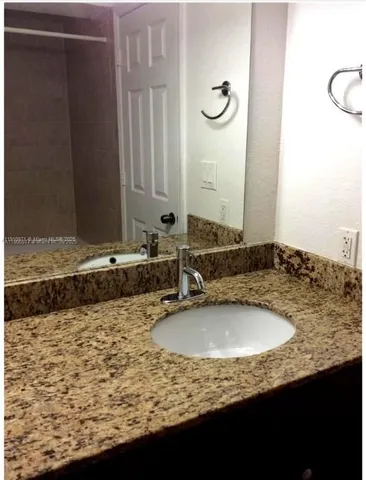 a bathroom with a granite countertop sink and a toilet