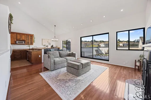 a living room with furniture large window and wooden floor