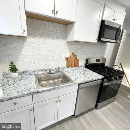 a kitchen with granite countertop a sink a stove and cabinets