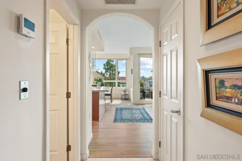 a view of a hallway with wooden floor and a livingroom with furniture