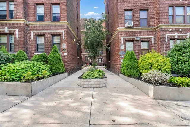 a front view of a multi story residential apartment building with yard and bench