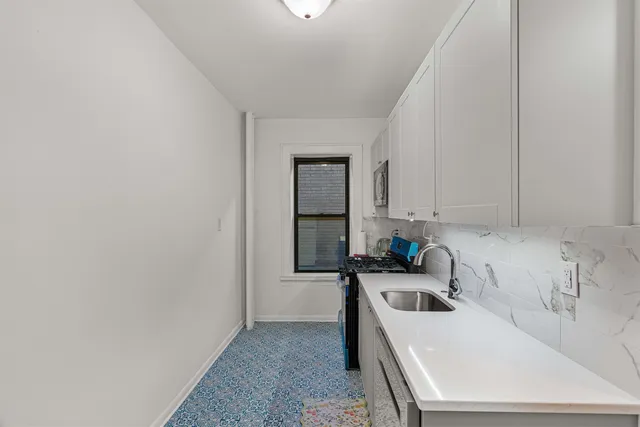 a kitchen that has a sink and a stove with white countertops