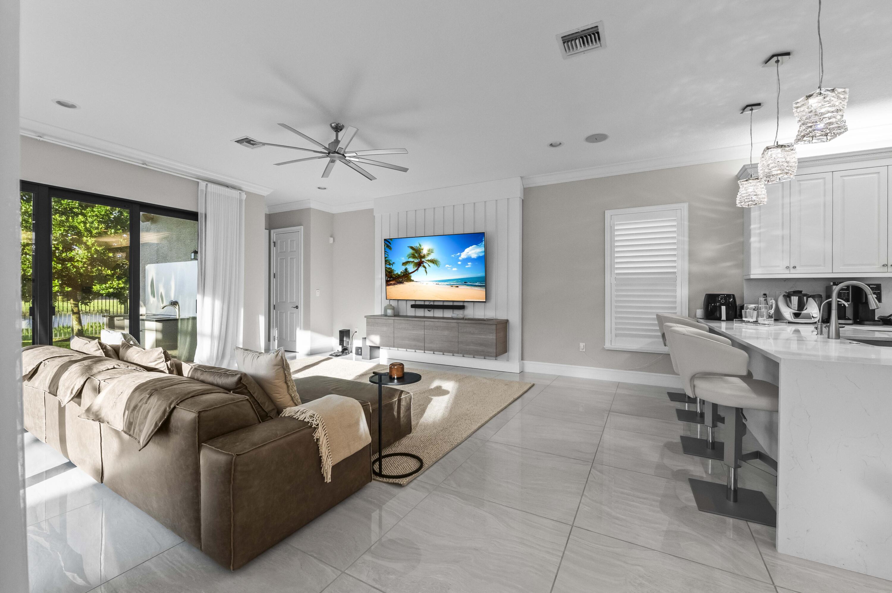 9795 Rennes Lane Delray Beach, FL 33446 - Photo 13 of 79 a living room with furniture a chandelier and a flat screen tv