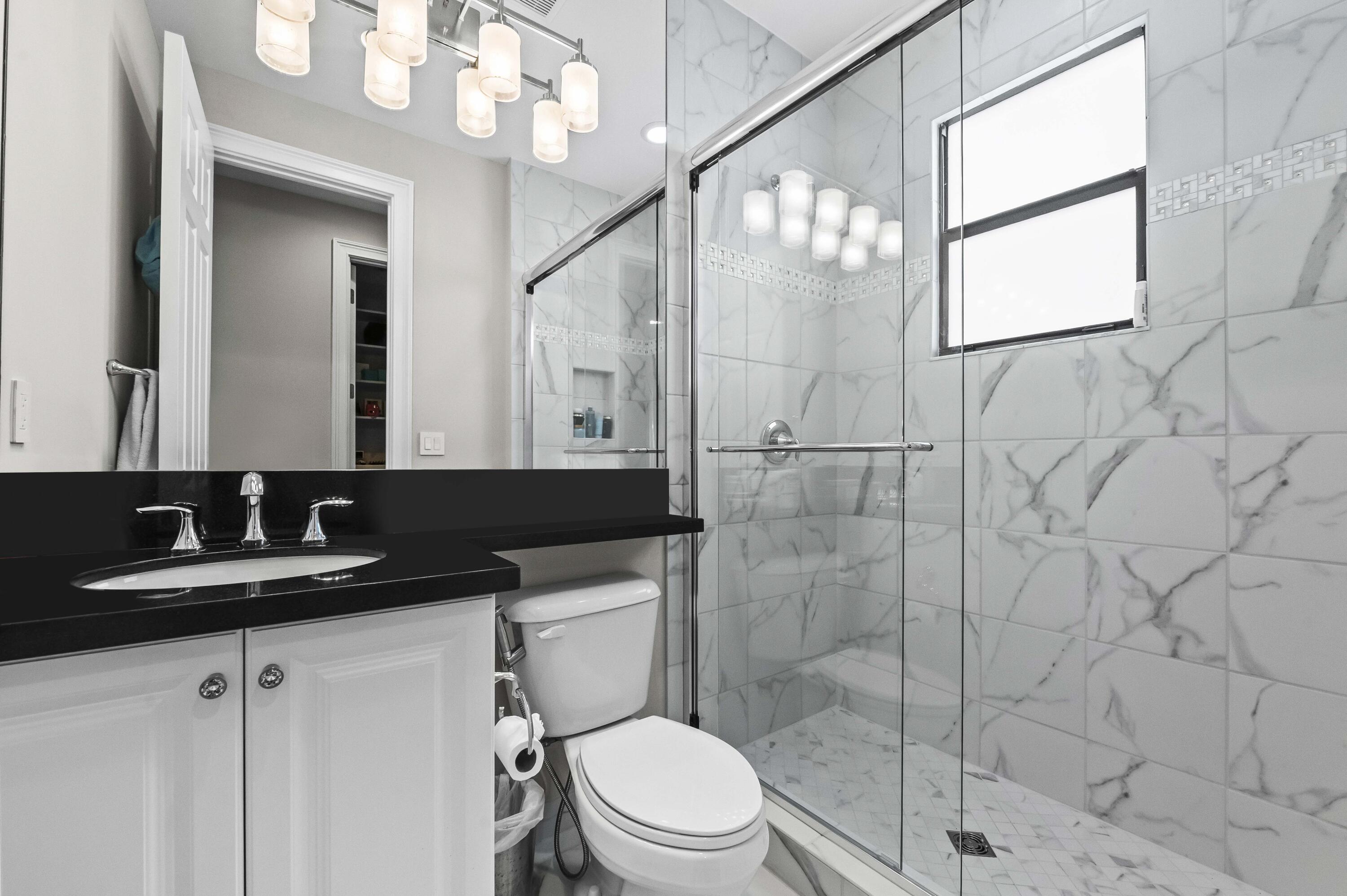 9795 Rennes Lane Delray Beach, FL 33446 - Photo 39 of 79 a bathroom with a granite countertop sink a toilet and a mirror