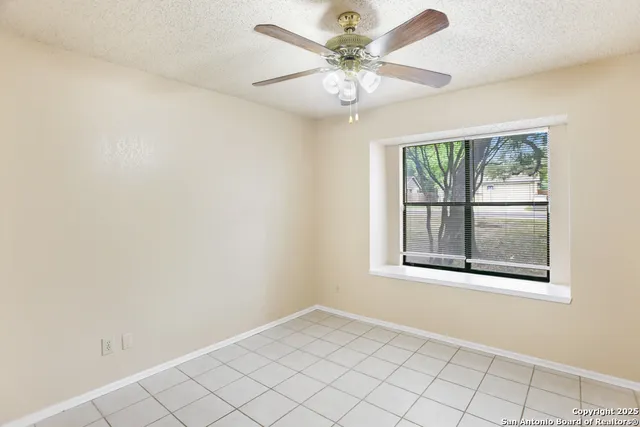 an empty room with windows and fan