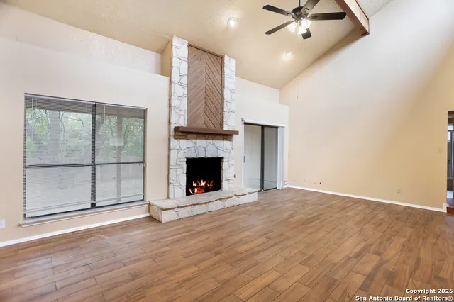 a view of an empty room with wooden floor fireplace and a window