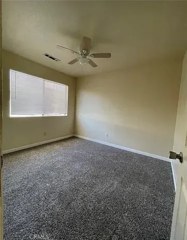 an empty room with windows and fan