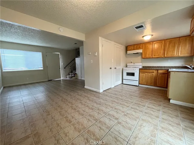 a view of a kitchen with a sink stove cabinets and empty room