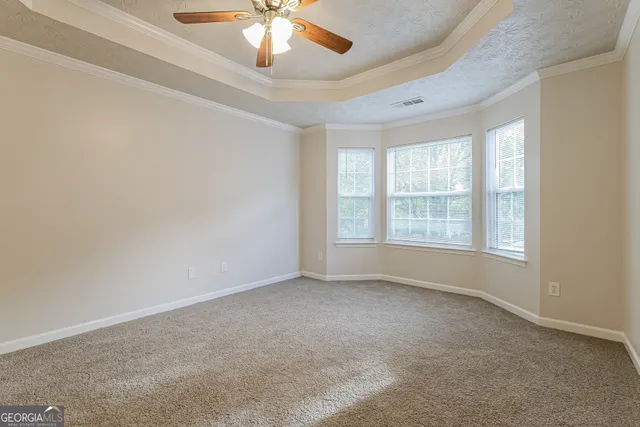 an empty room with a chandelier fan and windows