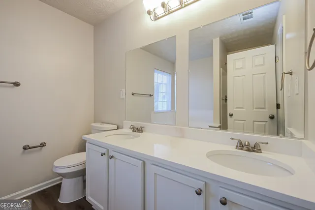 a bathroom with a granite countertop toilet a sink and a mirror