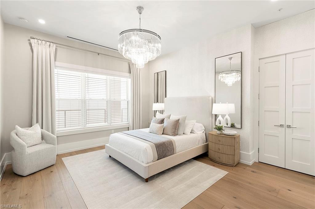 201 8th Street South, Unit 301 Naples, FL 34102 - Photo 23 of 43 a bedroom with a bed and a chandelier