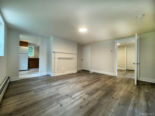 Unfurnished living room with dark wood finished floors and a baseboard radiator