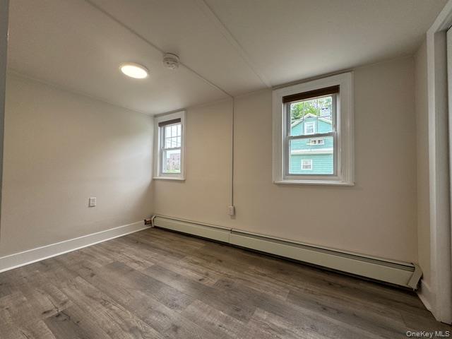 12 Grove Street, Unit C Beacon, NY 12508 - Photo 8 of 13 Empty room featuring a baseboard heating unit, wood finished floors, and a smoke detector