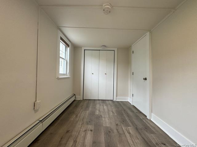 12 Grove Street, Unit C Beacon, NY 12508 - Photo 9 of 13 Unfurnished bedroom featuring a baseboard heating unit, dark wood-style flooring, and a closet