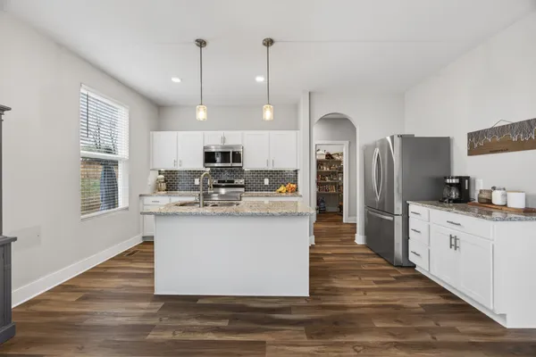 a living room with stainless steel appliances granite countertop furniture wooden floor and a window