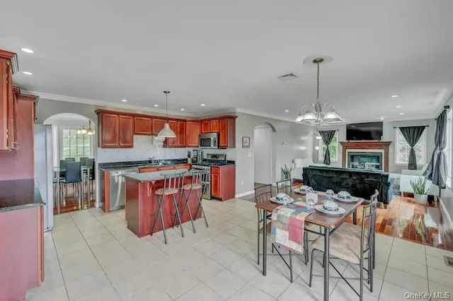 a kitchen with stainless steel appliances kitchen island granite countertop a table chairs and a sink