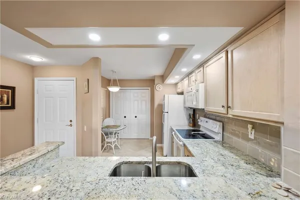 a large white kitchen with a large window and stainless steel appliances