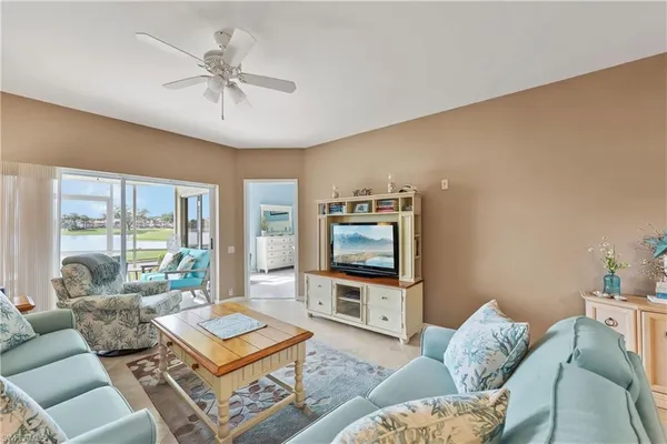 a living room with furniture a flat screen tv and a large window