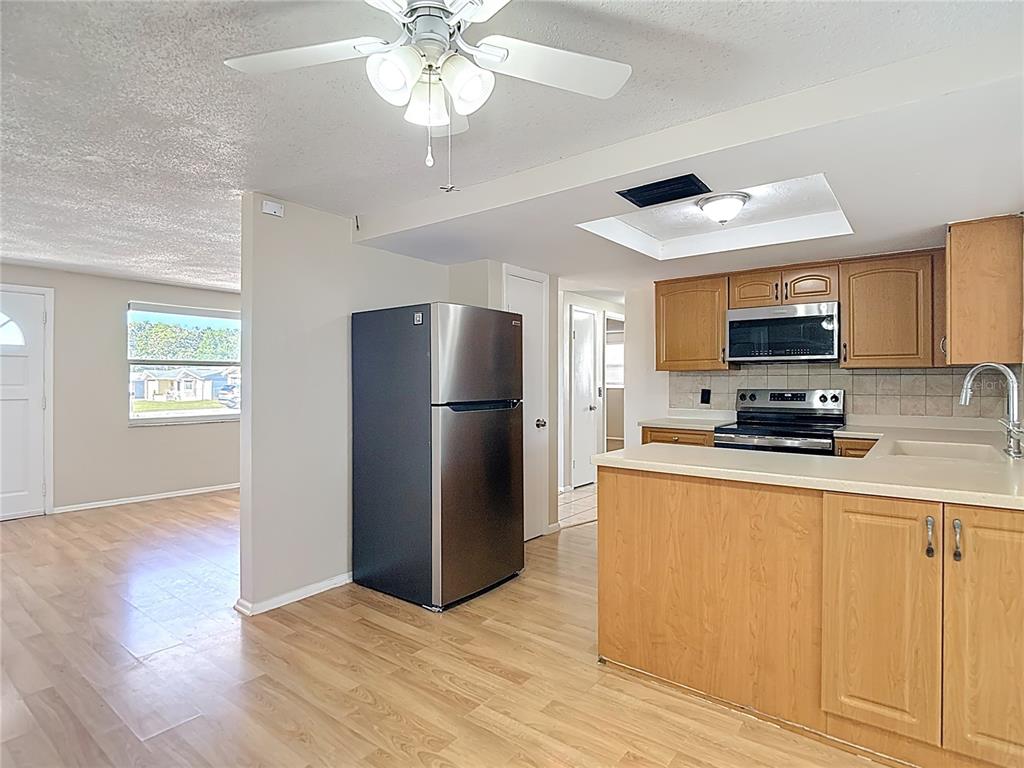 10806 Jason Road Port Richey, FL 34668 - Photo 12 of 46 a kitchen with stainless steel appliances granite countertop a refrigerator a stove top oven a sink and dishwasher with wooden floor