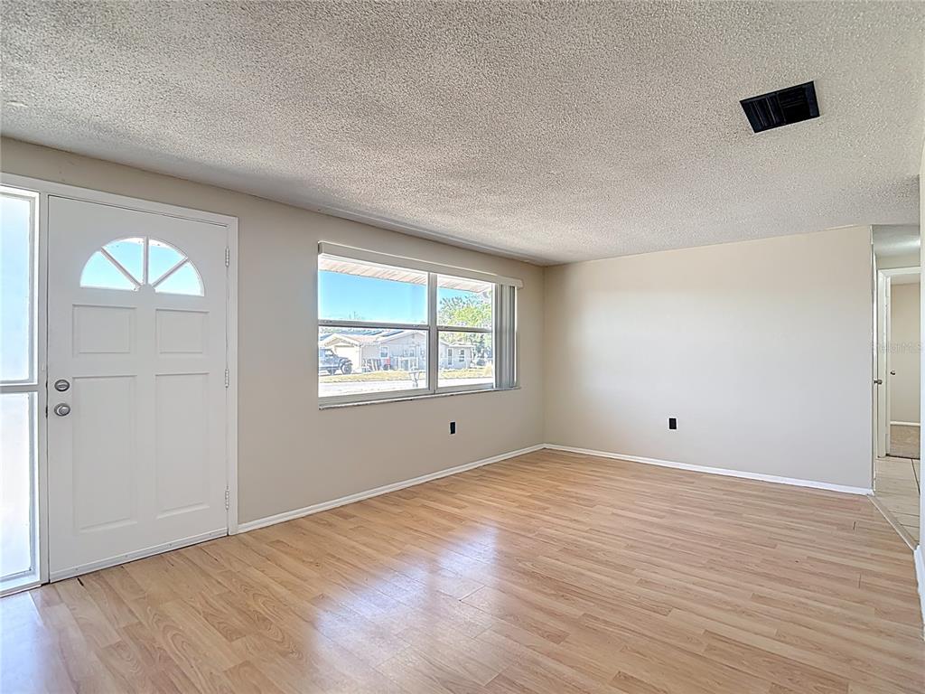 10806 Jason Road Port Richey, FL 34668 - Photo 5 of 46 a view of an empty room with wooden floor and a window