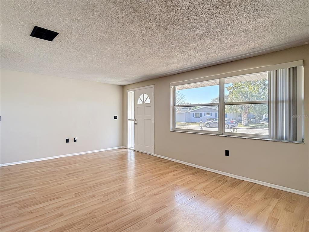 10806 Jason Road Port Richey, FL 34668 - Photo 8 of 46 a view of an empty room with wooden floor and a window