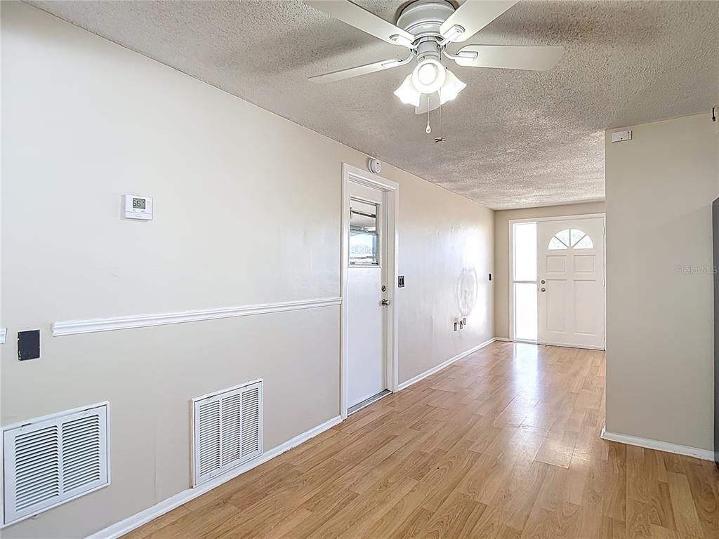 10806 Jason Road Port Richey, FL 34668 - Photo 9 of 46 a view of an empty room with chandelier fan and wooden floor