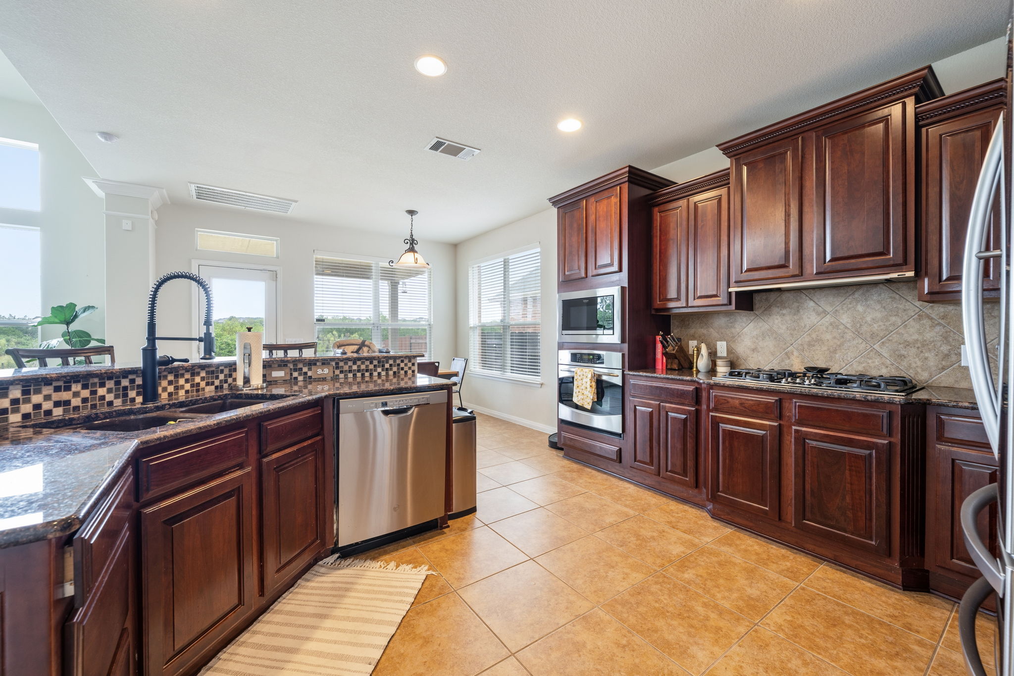 1581 Grassy Field Road Austin, TX 78737 - Photo 11 of 37 Rich wood cabinetry and expansive granite countertops define this beautifully designed culinary space.