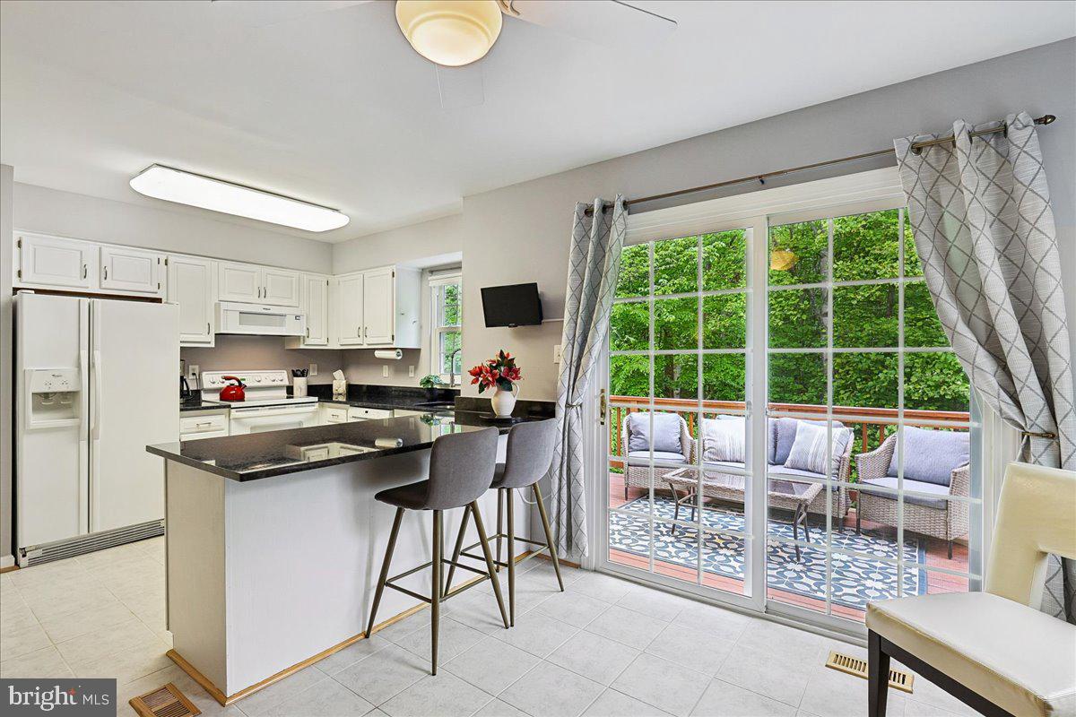 5211 Spring Branch Boulevard Dumfries, VA 22025 - Photo 8 of 32 a kitchen with stainless steel appliances granite countertop a stove top oven a sink dishwasher a dining table and chairs with wooden floor