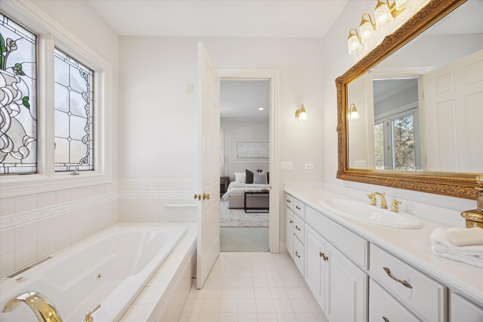 15W260 62nd Street Burr Ridge, IL 60527 - Photo 21 of 48 a bathroom with a bathtub a double vanity sink a vanity a window and a mirror