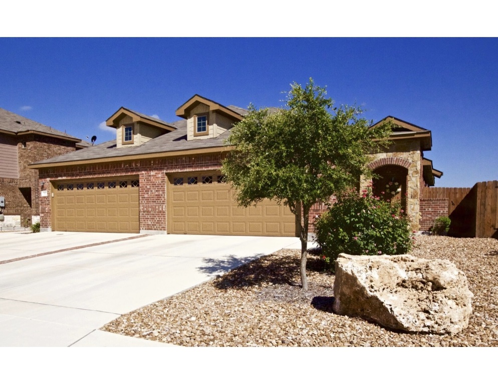 View of front facade with driveway, brick siding, and an attached garage