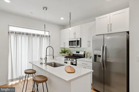 a kitchen with stainless steel appliances a refrigerator sink and white cabinets