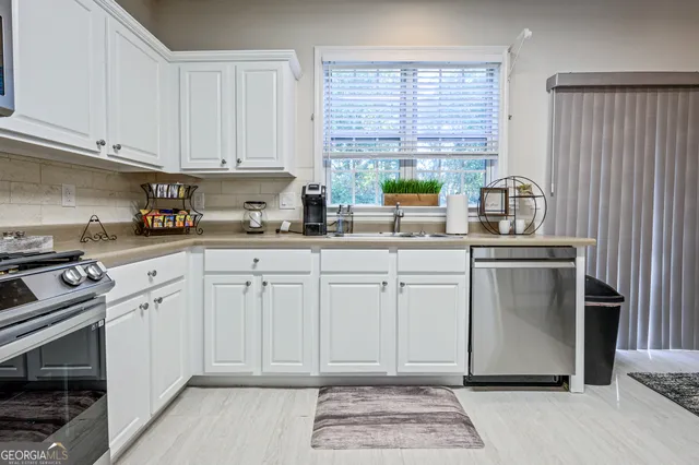 a kitchen with stainless steel appliances granite countertop a sink a stove a refrigerator and cabinets