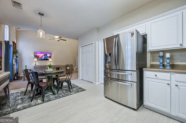 a kitchen with stainless steel appliances granite countertop a dining table chairs refrigerator and cabinets