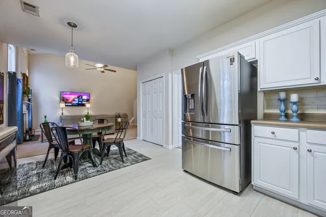 a kitchen with stainless steel appliances granite countertop a dining table chairs refrigerator and cabinets