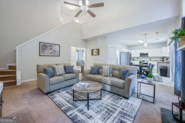 a living room with furniture kitchen view and a potted plant