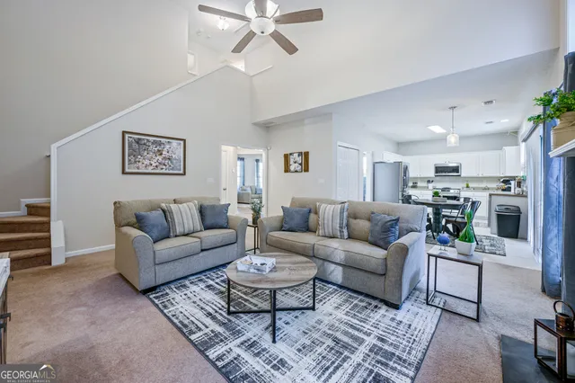 a living room with furniture kitchen view and a potted plant