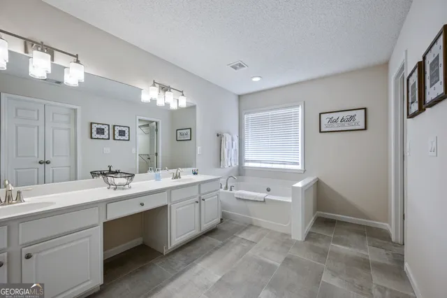 a spacious bathroom with a double vanity sink a large mirror and a bathtub