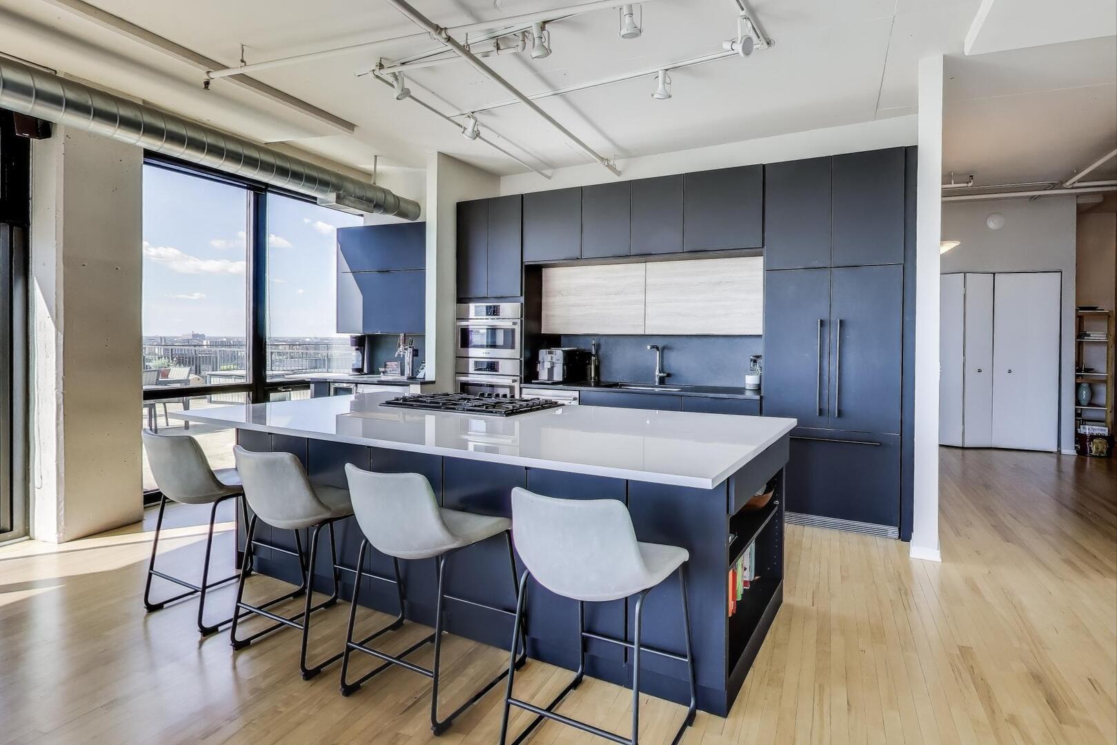 1530 South State Street, Unit 12J Chicago, IL 60605 - Photo 6 of 28 a kitchen with stainless steel appliances granite countertop a kitchen island a stove a table and chairs in it