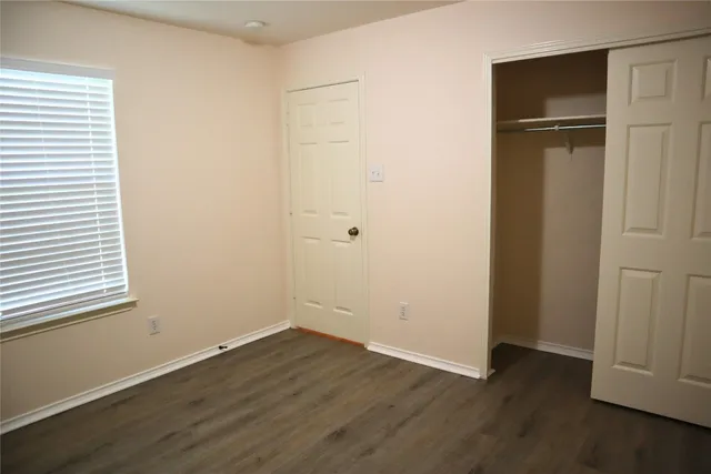 an empty room with wooden floor closet and fan