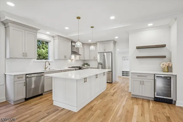 a large white kitchen with stainless steel appliances granite countertop a stove a sink dishwasher and a refrigerator