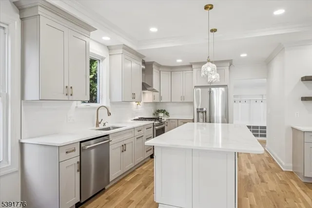 a kitchen with a sink a center island stainless steel appliances and cabinets