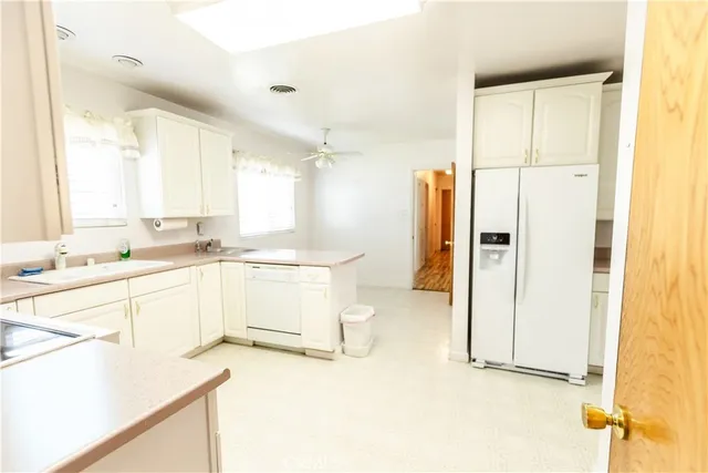 a large white kitchen with granite countertop a sink and a refrigerator
