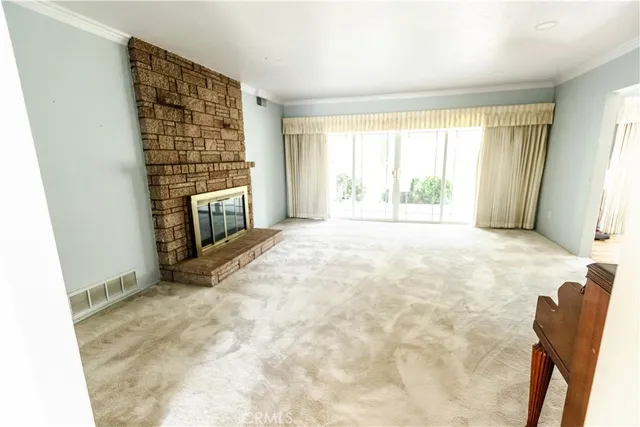 a view of an empty room with a fireplace and a window