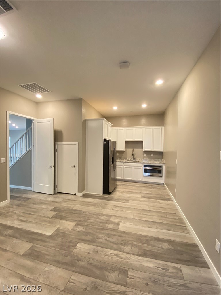 695 Daylight Ridge Court Henderson, NV 89052 - Photo 12 of 27 Kitchen featuring white cabinetry, light countertops, light wood-style flooring, and stainless steel fridge