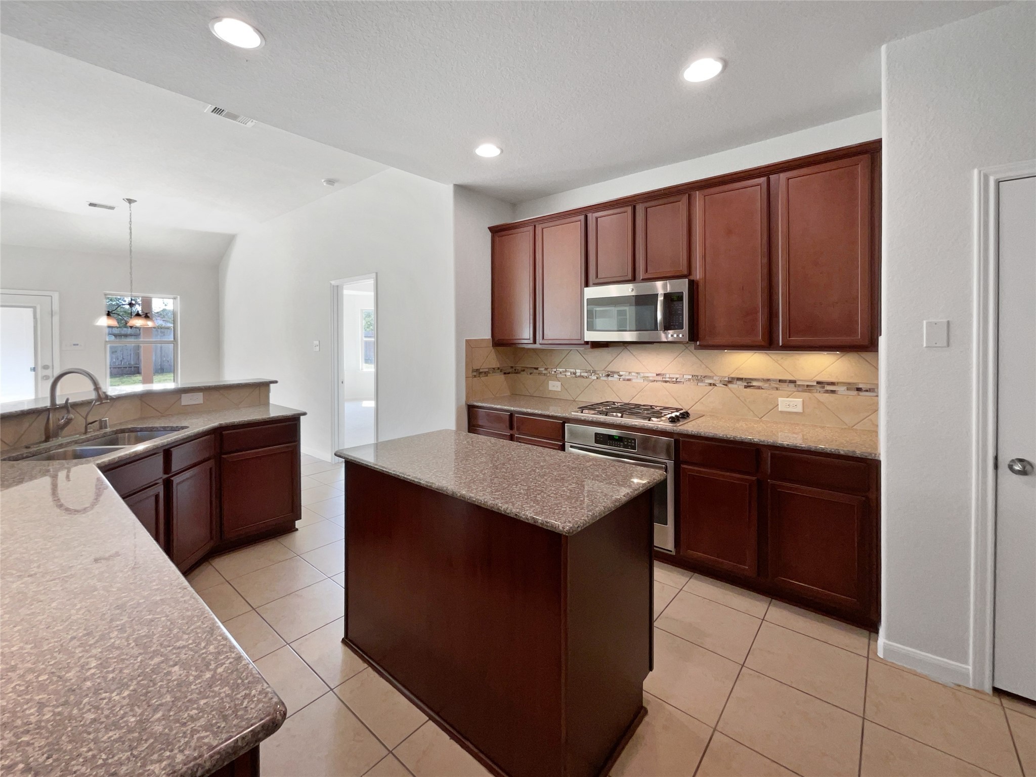 7323 Collins Manor Drive Spring, TX 77389 - Photo 10 of 22 a kitchen with kitchen island granite countertop wooden cabinets a sink and a stove