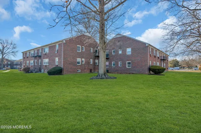a view of a brick house next to a yard with large trees