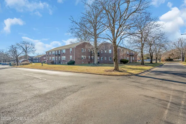 a brick house with a big yard plants and large trees