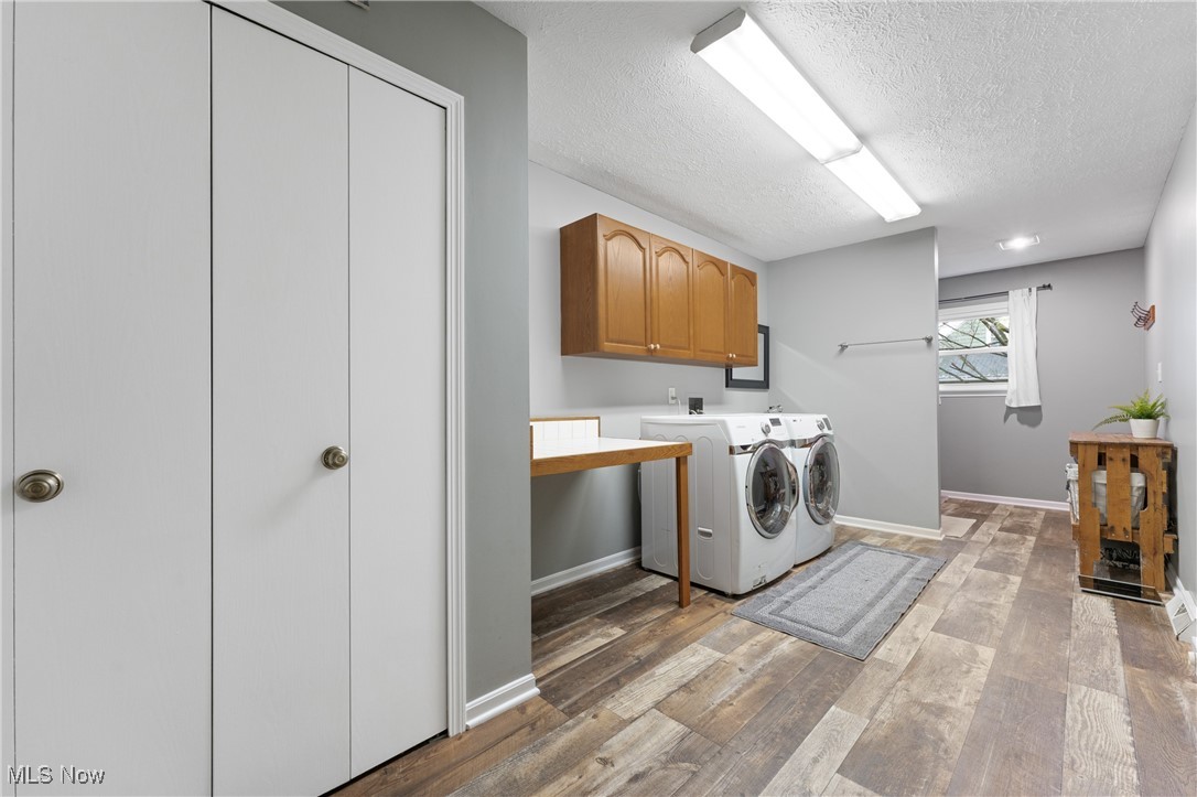 645 Killinger Road Clinton, OH 44216 - Photo 23 of 50 Laundry area featuring washing machine and clothes dryer, cabinets, a textured ceiling, and light wood-type flooring